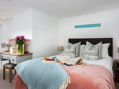 a bedroom with a bed with books and a table at The Loft in Porthleven