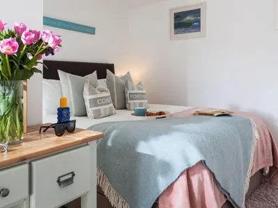 a bedroom with a bed with a vase of pink flowers at The Loft in Porthleven