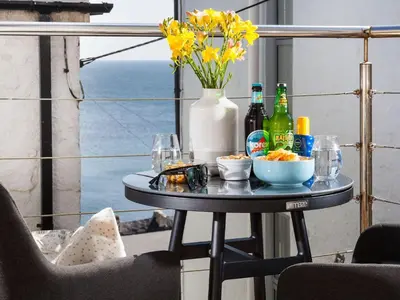 a table with drinks and a vase with yellow flowers at The Loft in Porthleven