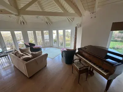 a living room with a piano and a couch at Penarvon House - Stunning Waterfront Escape with Games Room in Manaccan
