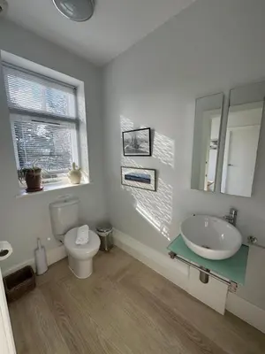 a bathroom with a sink and a toilet and a mirror at Penarvon House - Stunning Waterfront Escape with Games Room in Manaccan