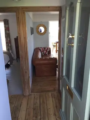 a brown leather couch sitting in a living room at Bay View Cottage - Amazing sea views and 3 bedrooms Sleeps 6-8 in Treknow