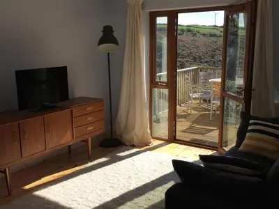 a living room with a television and a sliding glass door at Bay View Cottage - Amazing sea views and 3 bedrooms Sleeps 6-8 in Treknow