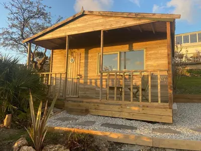 a log cabin with a porch and chairs in a yard at Bay View Cottage - Amazing sea views and 3 bedrooms Sleeps 6-8 in Treknow