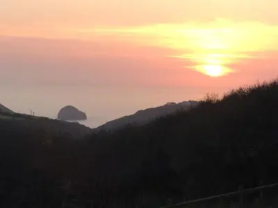 a sunset over a hill with the ocean in the background at Bay View Cottage - Amazing sea views and 3 bedrooms Sleeps 6-8 in Treknow