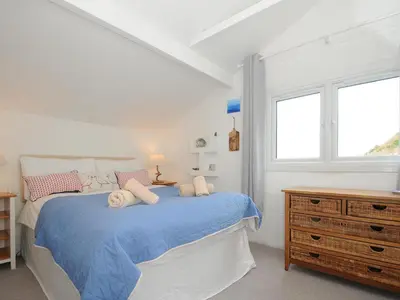 a white bedroom with a bed and a dresser at Little Ruffo in Tintagel