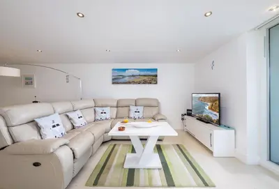 a living room with a white couch and a tv at 25 Rocklands in Newquay in Newquay