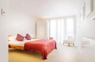 a bedroom with a bed with a red blanket and a chair at Cinq 5 Zinc in Fistral, Newquay in Newquay