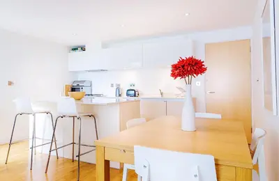 a kitchen with a wooden table and a vase with red flowers at Cinq 5 Zinc in Fistral, Newquay in Newquay