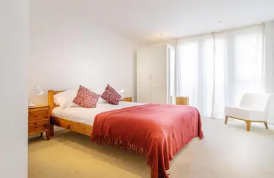 a bedroom with a bed with a red blanket and a chair at Cinq 5 Zinc in Fistral, Newquay in Newquay