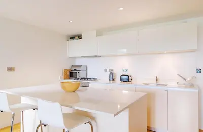 a kitchen with white cabinets and a white counter top at Cinq 5 Zinc in Fistral, Newquay in Newquay