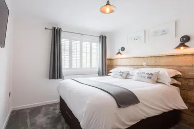 a bedroom with a large bed with white sheets and pillows at Sandcastles 11 Europa Court in Mawgan Porth in Mawgan Porth