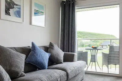 a living room with a couch and a large window at Sandcastles 11 Europa Court in Mawgan Porth in Mawgan Porth