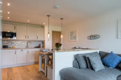 a living room with a couch and a kitchen at Sandcastles 11 Europa Court in Mawgan Porth in Mawgan Porth