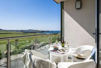 a balcony with a table and chairs and a view of the ocean at Surfside 34 Zinc in Newquay in Newquay