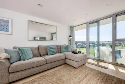 a living room with a couch and a large window at Surfside 34 Zinc in Newquay in Newquay