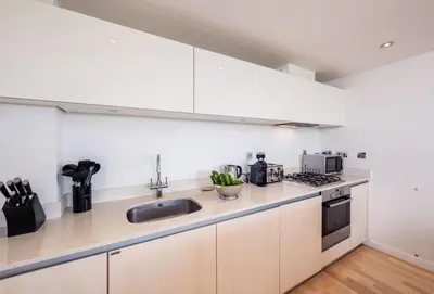 a kitchen with white cabinets and a sink at Surfside 34 Zinc in Newquay in Newquay