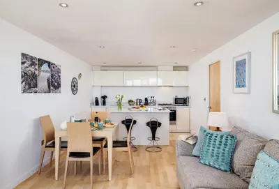 a kitchen and living room with a table and a couch at Surfside 34 Zinc in Newquay in Newquay
