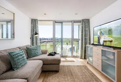 a living room with a couch and a flat screen tv at Surfside 34 Zinc in Newquay in Newquay