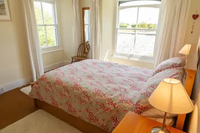 a bedroom with a bed and a table with a lamp at Lamledra Farm House Apartment in Gorran Haven