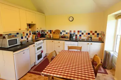 a kitchen with a table with a checkered table cloth at Lamledra Farm House Apartment in Gorran Haven