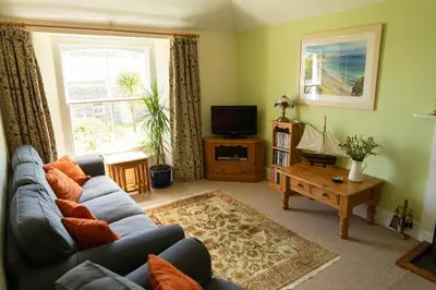 a living room with a blue couch and a tv at Lamledra Farm House Apartment in Gorran Haven
