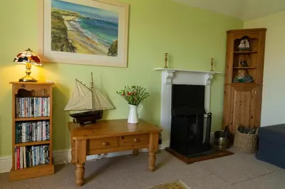 a living room with a fireplace and a table with a boat on it at Lamledra Farm House Apartment in Gorran Haven