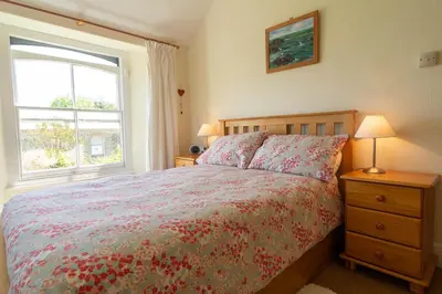 a bedroom with a large bed and a window at Lamledra Farm House Apartment in Gorran Haven