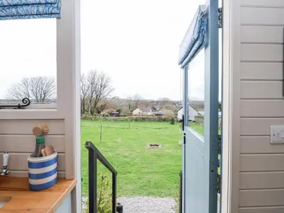 a door to a yard with a view of a field at Teg in Helston
