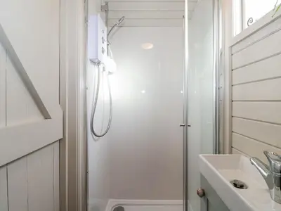 a white bathroom with a shower and a sink at Teg in Helston