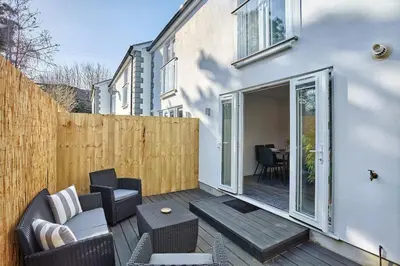 a patio with chairs and a table and a fence at 2022 Modern Home In Central Hayle With Parking & EV plug in Hayle