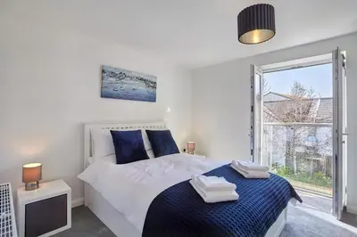 a bedroom with a bed with blue pillows and a window at 2022 Modern Home In Central Hayle With Parking & EV plug in Hayle