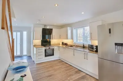 a kitchen with white appliances and wooden floors at 2022 Modern Home In Central Hayle With Parking & EV plug in Hayle