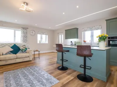 a kitchen and living room with green cabinets at Little Hillside in Redruth