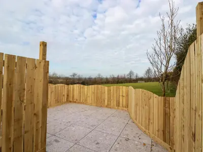 a wooden fence with a patio in front of it at Little Hillside in Redruth