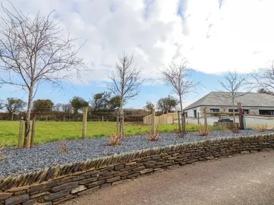a stone retaining wall with trees in a yard at Little Hillside in Redruth