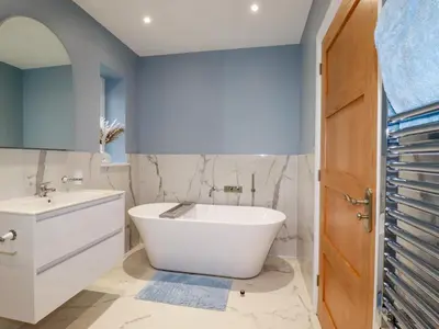 a bathroom with a white tub and a sink at Little Hillside in Redruth