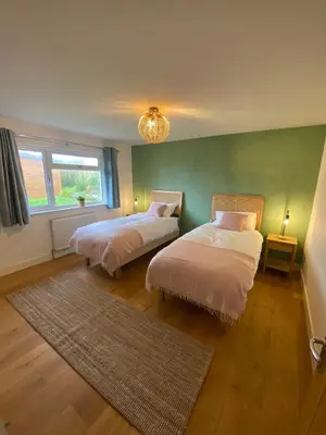 a bedroom with two beds and a green wall at Elisa Villa - tranquil retreat 5 mins from the sea in Port Isaac
