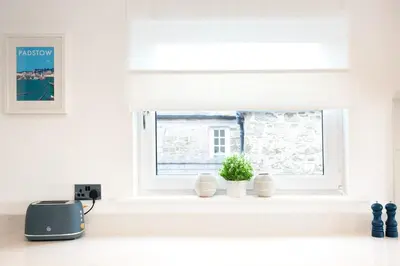 a window in a kitchen with two plants on a counter at Elisa Villa - tranquil retreat 5 mins from the sea in Port Isaac