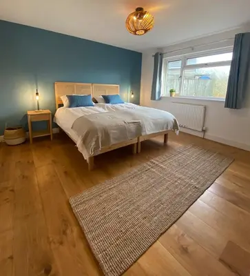 a bedroom with a bed with a rug and a window at Elisa Villa - tranquil retreat 5 mins from the sea in Port Isaac