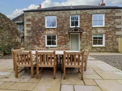 a table and chairs in front of a brick house at Tretoil Farm House in Bodmin