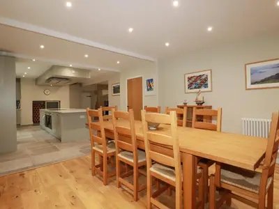 a kitchen and dining room with a wooden table and chairs at Tretoil Farm House in Bodmin