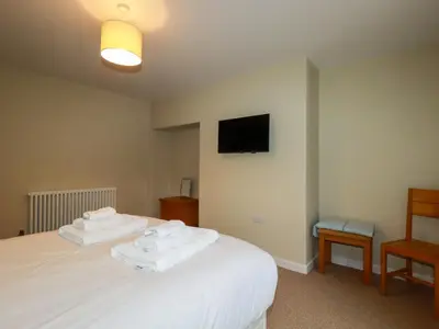 a bedroom with two towels on a bed with a tv at Tretoil Farm House in Bodmin