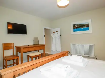 a bedroom with a bed and a desk and a television at Tretoil Farm House in Bodmin