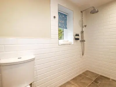 a white bathroom with a shower and a toilet at Tretoil Farm House in Bodmin