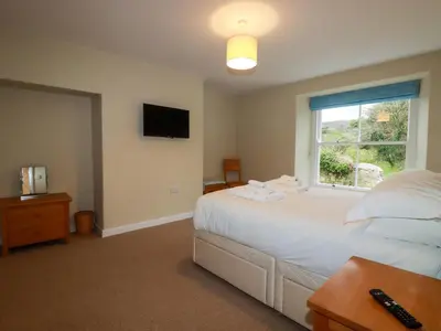 a bedroom with a white bed and a window at Tretoil Farm House in Bodmin