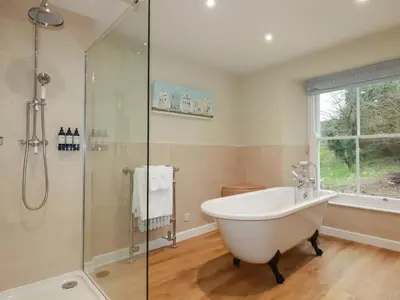 a bathroom with a tub and a glass shower at Tretoil Farm House in Bodmin