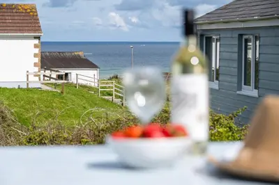 a bottle of wine sitting on a table with a bowl of fruit at WestHill Beach Chalet, Riviere Towans in Hayle