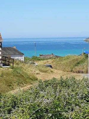 a house on a hill with the ocean in the background at WestHill Beach Chalet, Riviere Towans in Hayle