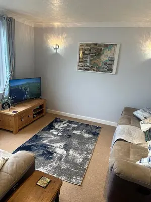 a living room with a couch and a flat screen tv at Penolva Beach Side Apartment in Perranporth